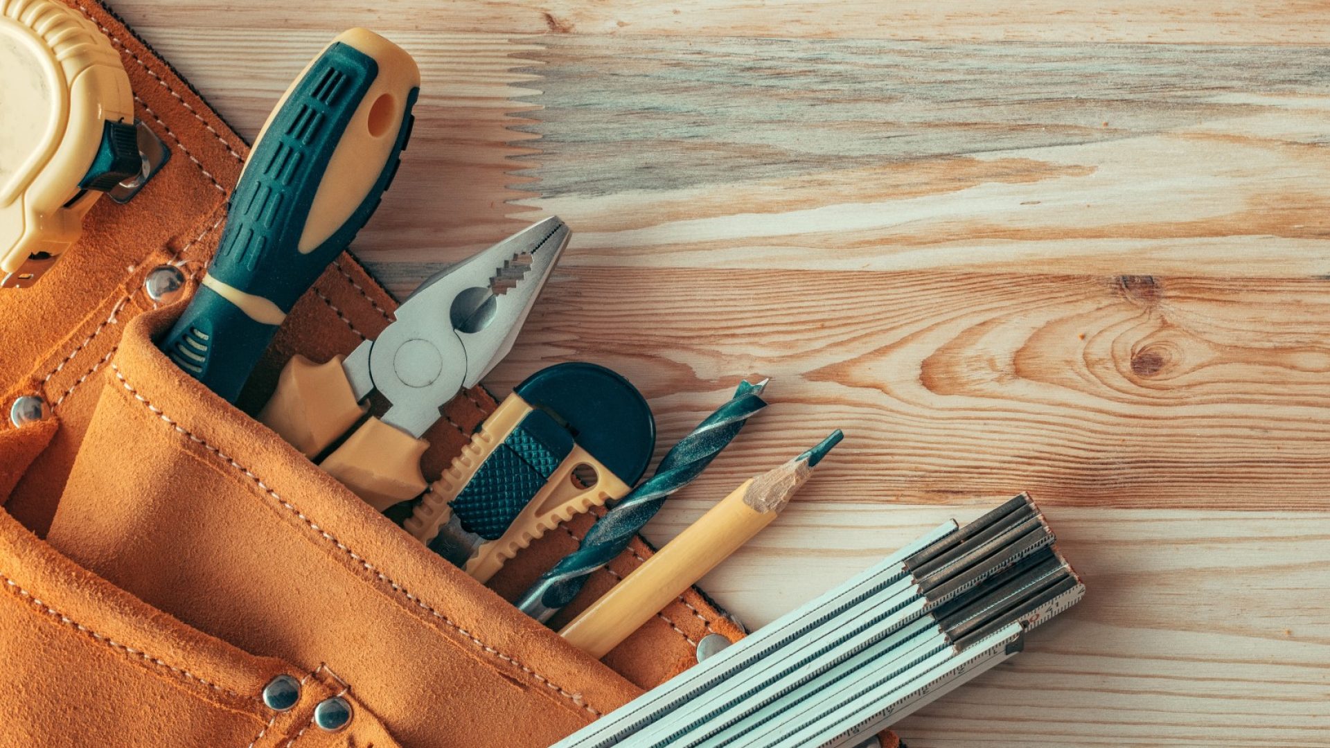 Carpentry tool belt on woodwork workshop desk with assorted tools of trade, top view with copy space