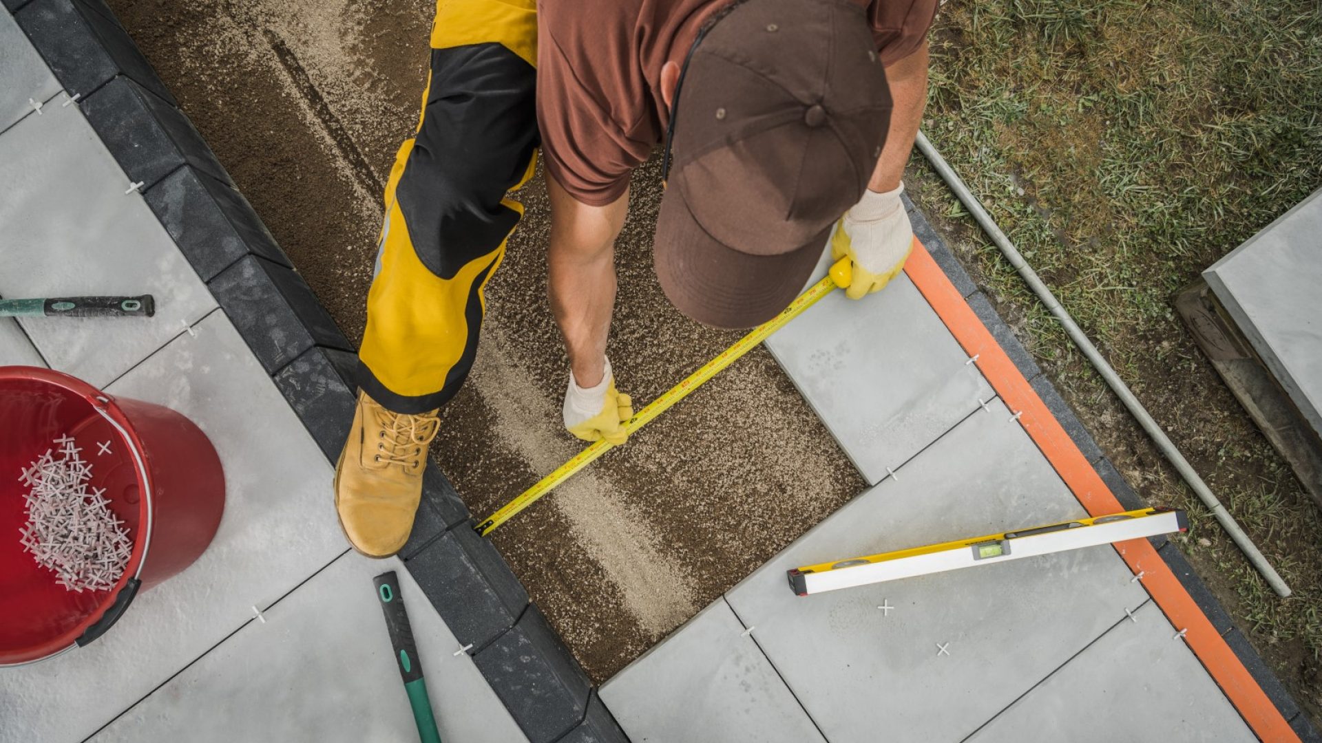 Caucasian Small Architecture Worker Paving Residential Patio Area by Placing Outdoor Concrete Tiles. Industrial Theme.