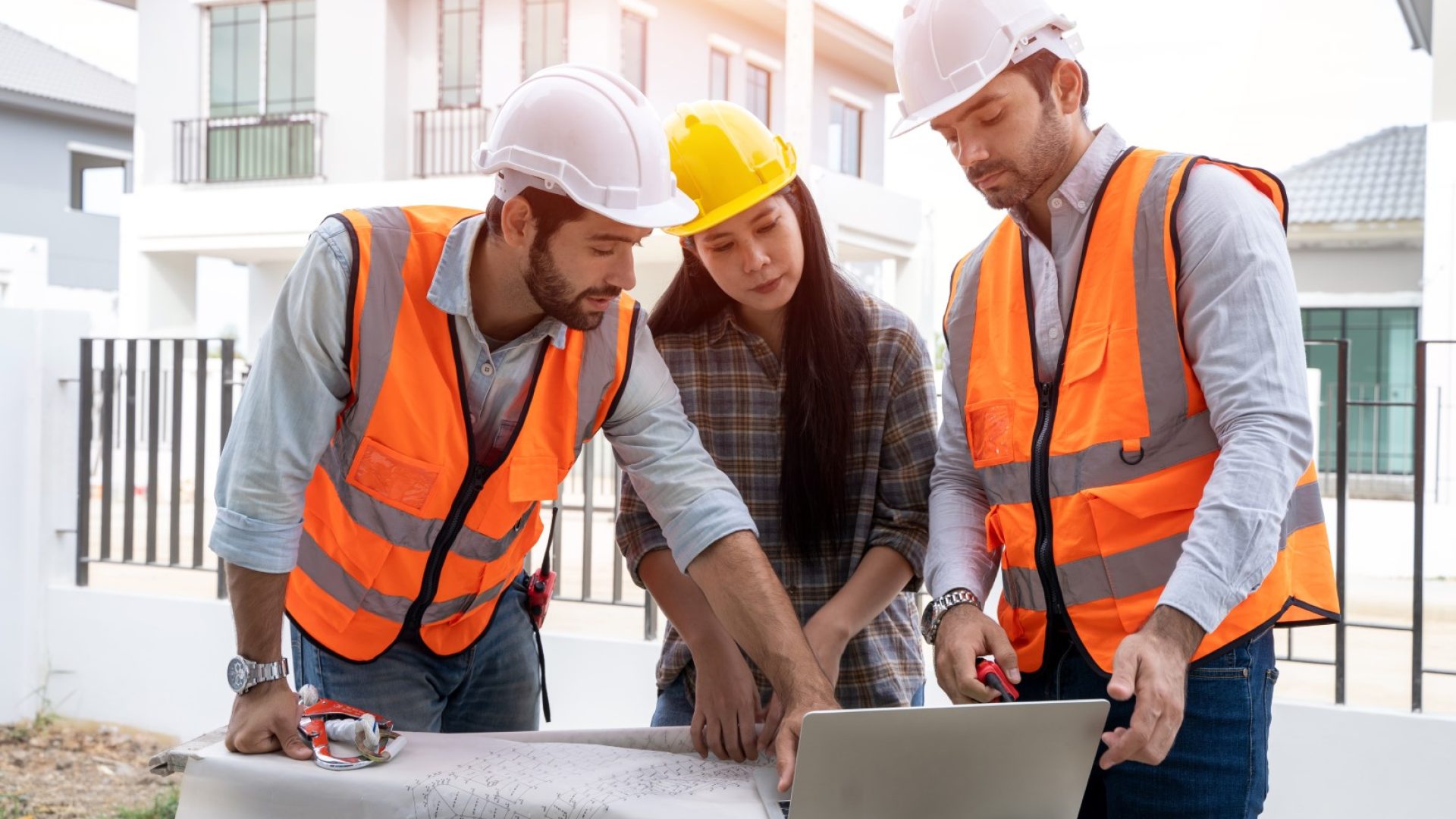 Engineer team discuss and planning from work site about construction  house project with blueprint drawing paper and computer laptop.